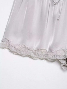Detail of silk satin shorts featuring delicate lace trim and adjustable drawstring waist