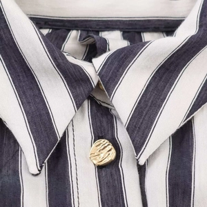 Detailed macro view of navy blue striped linen shirt collar with gold embossed button