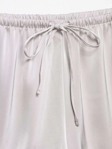 Detail of silver satin shorts showing the elastic waistband and adjustable drawstring