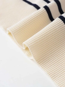 Close-up of cream knit fabric with navy stripes and ribbed hem detail for texture