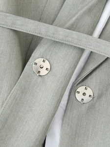 Detail of grey woven blazer featuring a waist belt and two silver metal buttons