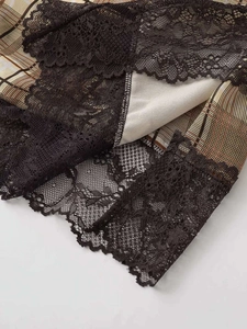 Détail de dentelle noire florale cousue sur tissu à carreaux marron avec doublure