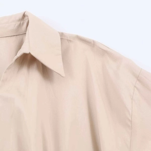 Detail of minimalist beige long-sleeve dress with pointed collar and drop shoulder seams