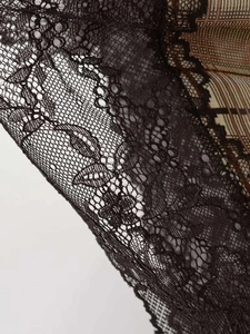 Détail de dentelle florale noire sur tissu à carreaux marron pour un haut en satin doux