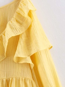 Detail shot of bright yellow tiered ruffles and pleated texture fabric on summer top