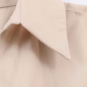 Close-up detail of the beige midi dress collar and stitching on smooth plain weave fabric