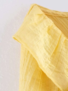 Detailed view of the yellow ruffle neckline featuring textured crinkle fabric texture