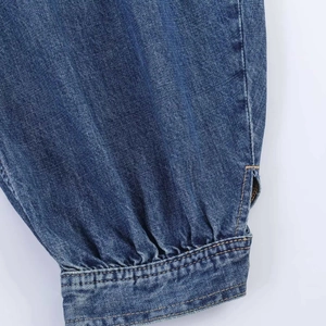 Detail view of denim balloon pants featuring pleated cuffs and yellow contrast stitching