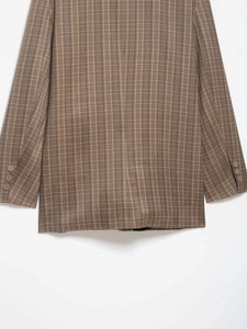 Détail d'une veste à carreaux marron vintage avec trois boutons de manche marron