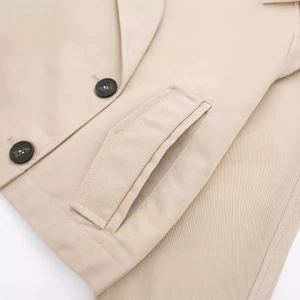 Nahaufnahme einer beigen Kurzjacke mit klassischem Reverskragen und dunklem Knopf