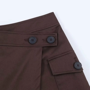 Detail of dark brown twill skort featuring wrap waist design and cargo pocket with button