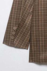 Détail de trois boutons marrons sur le poignet d'un blazer vintage à carreaux