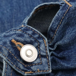 Macro detail of high-quality dark blue denim fabric with orange stitching and silver metal button