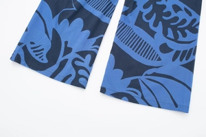 Detail view of wide-leg trousers featuring abstract blue floral patterns and neat hemline