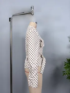 Detail of white long sleeve polka dot shirt featuring chest pocket and waist belt tie