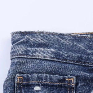 Detail view of denim jeans featuring raw hem waist and vintage washed blue fabric