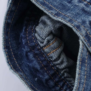 Macro view of blue denim fabric showing orange double stitching and pleated seam detail