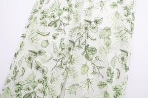 Détail de l'imprimé botanique vert sur le tissu blanc léger du pantalon pour femmes