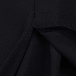 Macro detail of the high-quality stitching and slit design on the black woven dress