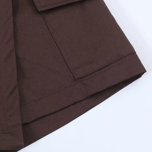 Close-up of brown cotton twill fabric showing square patch pocket and durable double stitching