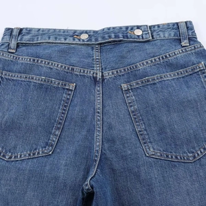 Macro detail of classic blue denim pants showing rear pockets and contrast stitching