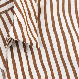 Detail of brown and white seersucker striped fabric with textured collar finish