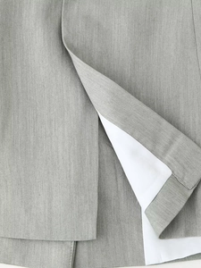 Close-up of light gray blazer slit detail showing high-quality stitching and white lining