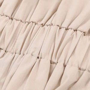 Detailed macro view of high-quality pleated smocking fabric on a beige midi dress