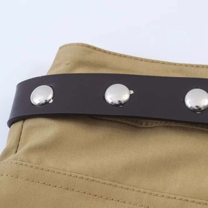 Details aus khakifarbenem Canvas mit Doppelnaht und braunem Leder-Nietengürtel