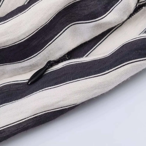 Close-up of black invisible zipper on striped sleeveless dress with woven fabric texture