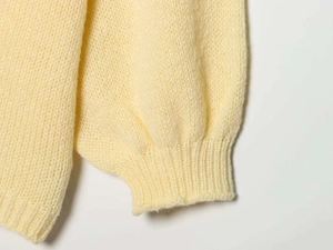 Detailed close-up of the ribbed cuff on a soft cream yellow chunky knit cardigan