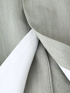 Close-up of premium gray twill suit fabric texture with neat white lining and stitching