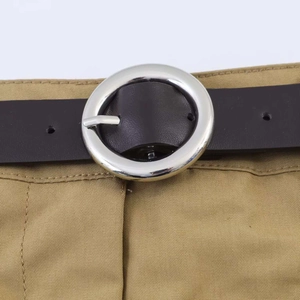 Detail eines schwarzen Ledergürtels mit silberner Metallschnalle auf einer Khaki-Hose