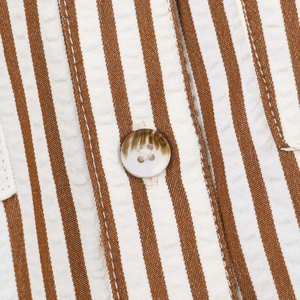 Macro shot of striped seersucker fabric featuring a marble-textured button and neat stitching