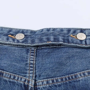 Detail of blue denim waist with double silver buttons and orange contrast stitching
