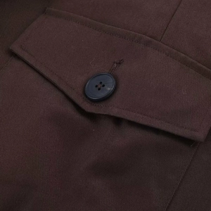 Detail of high-density twill fabric and premium button on a dark brown jacket pocket