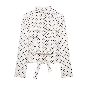 Detail of polka dot shirt featuring a mandarin collar and waist belt detail