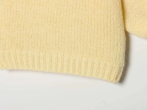 Detail of light yellow knit cardigan featuring plush mohair texture and ribbed hem edge