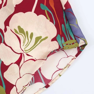 Detailed view of floral print blouse showing maroon satin fabric and fine hem stitching