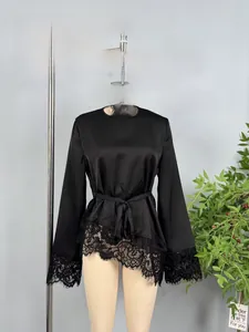Detail of black satin top with waist tie and delicate floral lace asymmetrical hemline