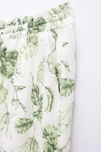 Détail du pantalon blanc à imprimé floral vert avec taille élastique et poches latérales