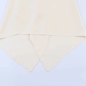 Close-up of asymmetric pointed handkerchief hem on light beige halter top fabric