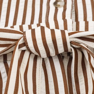 Macro view of seersucker striped fabric with a tied belt and textured brown button detail