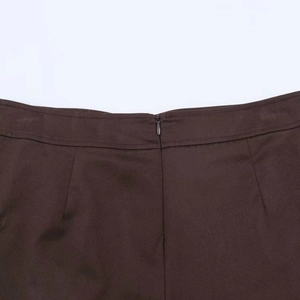 Detail view of the seamless invisible zipper on high-waist dark brown textured skirt pants