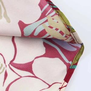 Detailed view of floral satin fabric showing precise stitching and vibrant flower patterns