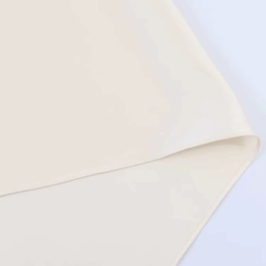 Detailed close-up of premium cream asymmetric top fabric with smooth silk-like texture