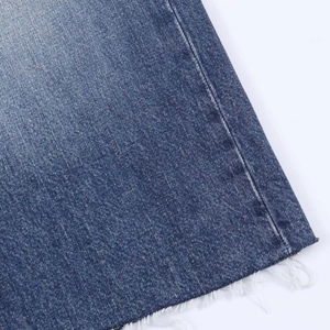 Detailed macro view of the raw hem on medium blue denim jeans with loose white threads