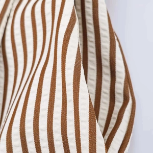 Detail of seersucker fabric with brown and white vertical stripes for summer jumpsuit