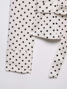 Detailed view of polka dot shirt cuff and matching waist belt with fabric texture