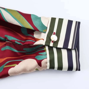 Close-up of vintage floral satin shirt cuff with striped fabric and gold button detail